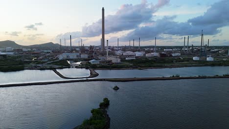 aerial pullback over water establishes flare stacks of oil refinery