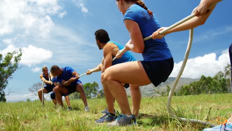 fit people playing tug of war during obstacle training course 4k