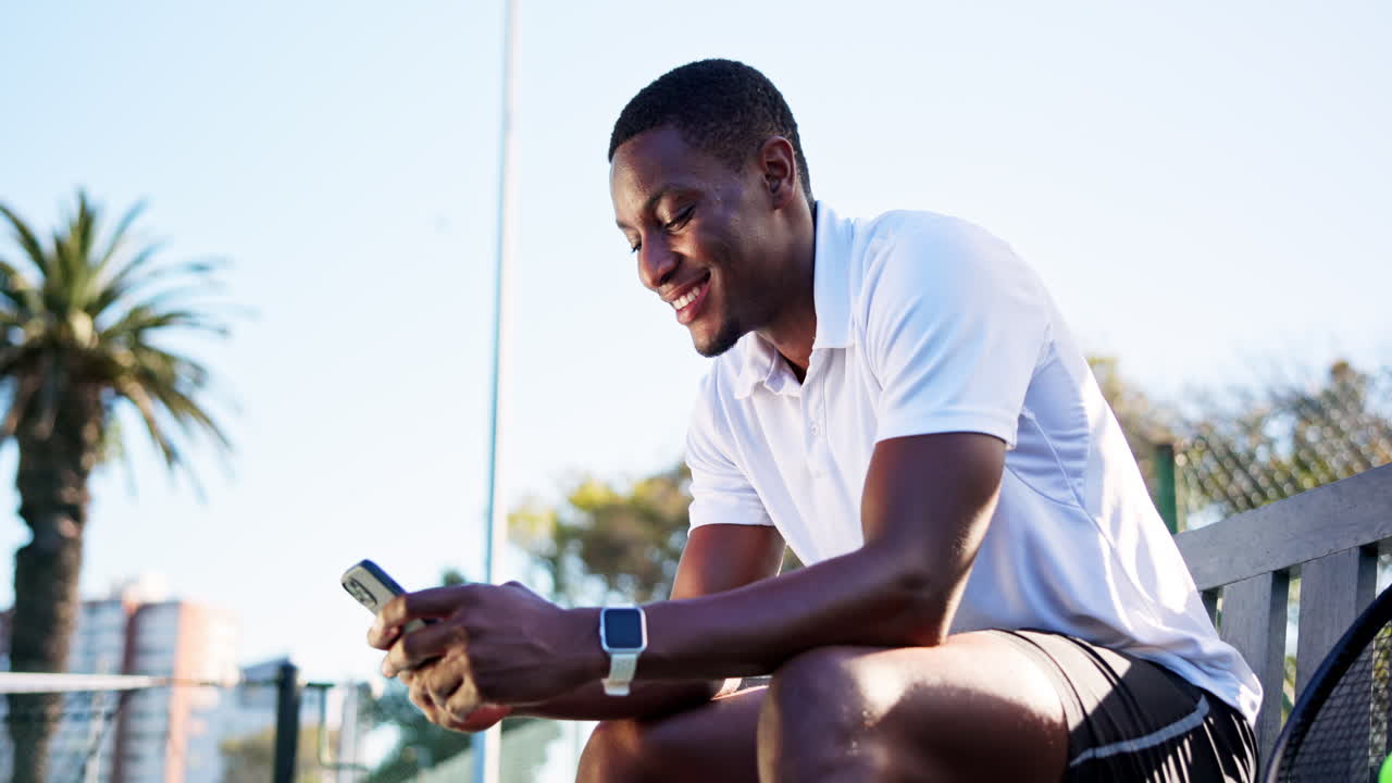 Happy Young Man Smiling and Using Smartphone on Tennis Court