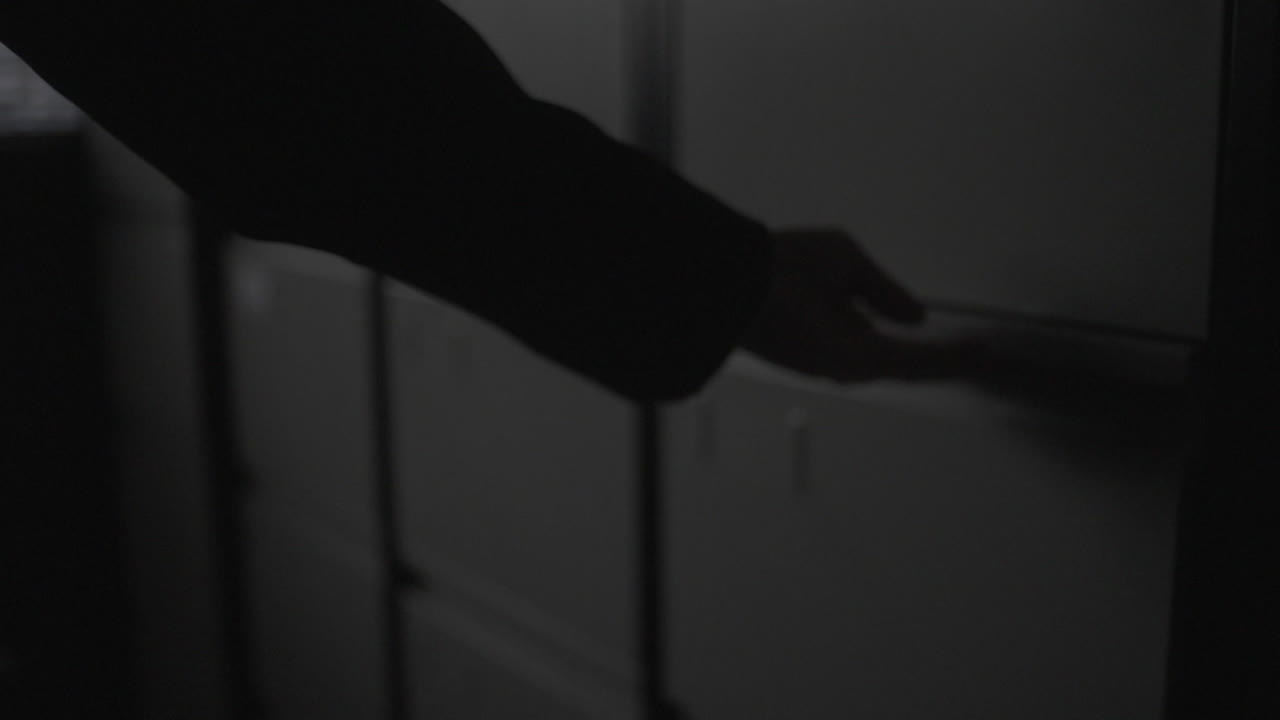 Person opening a file drawer in a dark office