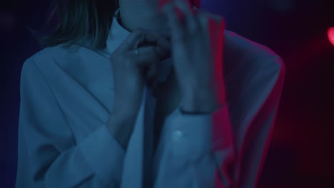 woman adjusting shirt collar under neon lighting