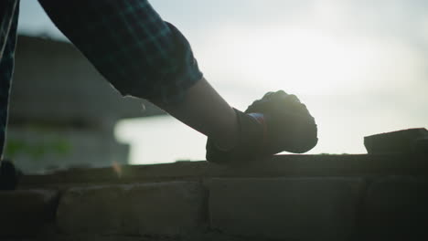 back view of an individual in a checkered shirt wearing a protective glove, with their hand clamped into a fist resting on a window ledge