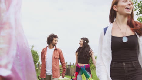 Group-Of-Excited-Young-Friends-Carrying-Camping-Equipment-Through-Field-To-Music-Festival