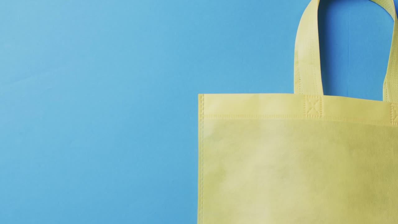 video de una bolsa de lona amarilla con espacio de copia en un fondo azul