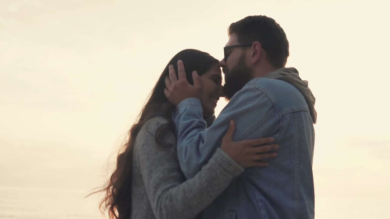 una pareja disfrutando de una puesta de sol romántica en la playa.