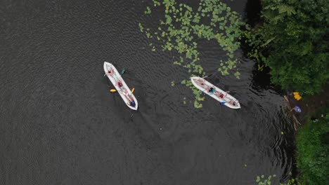 aerial birds-eye view of two canoes filled with people paddling in a river in the wilderness