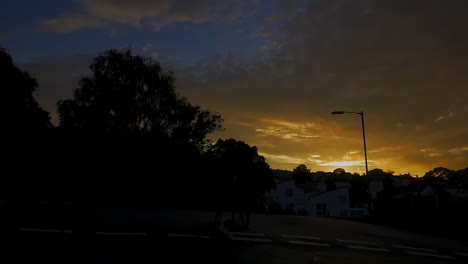 Man-pushes-bike-across-street-at-sundown,-wide