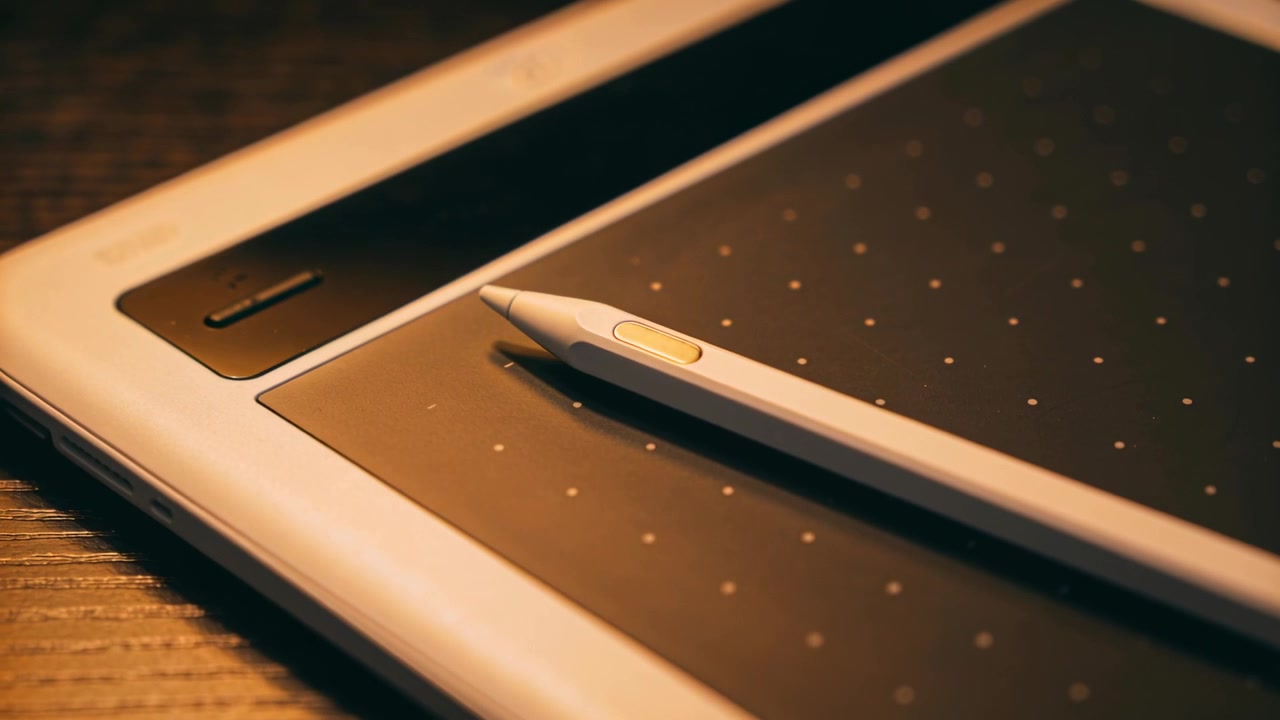Bevægende kamera indrammer digital stylus og grafiktablet på et træskrivebord, fremhæver sideknappen.