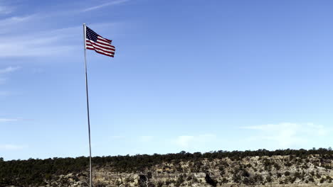 Un-Plano-Medio-De-Una-Bandera-De-Los-Estados-Unidos-De-América-Siguiendo-El-Viento-Con-Vistas-Al-Gran-Cañón