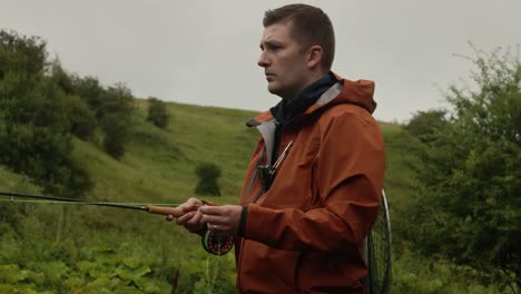 medium shot of a man flyfishing and casting his line into a stream in scotland