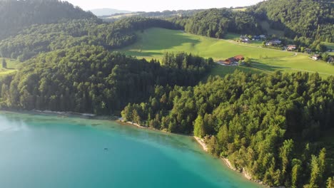 sensational aerial of austrian lake, vibrant blue water, green forest, sunny day