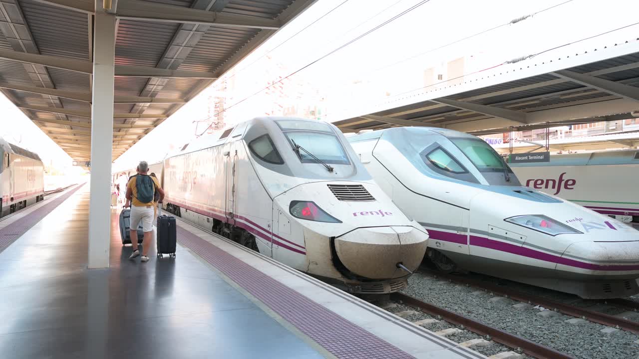 Passengers walk to board Renfe's high-speed AVE trains on the platform at Alicante station in Spain.