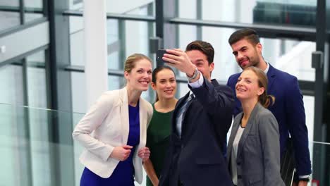 executivos de negócios tirando selfies em telefones celulares no corredor