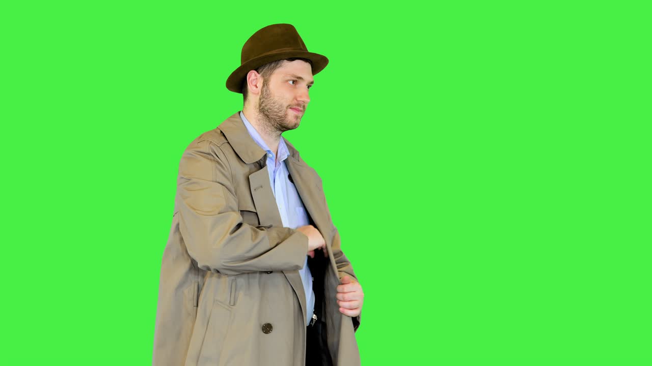 oficial de policía caucásico con abrigo retro y sombrero muestra la insignia del certificado para la investigación de delitos en una pantalla verde, llave cromada