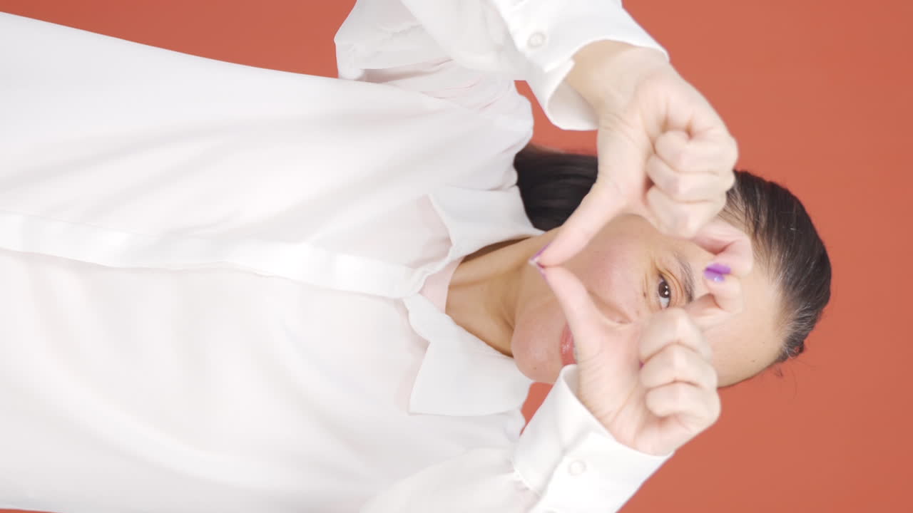 Vertical video of Woman making heart sign at camera.
