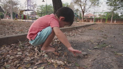 two year old asian boy having fun playing with the sand in an outdoor park getting his hands dirty