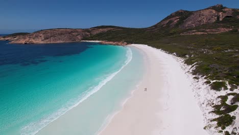 video de drone de 4k de una pareja corriendo a lo largo de la playa de arena blanca junto al océano azul cristalino en thistle cove, esperance wa