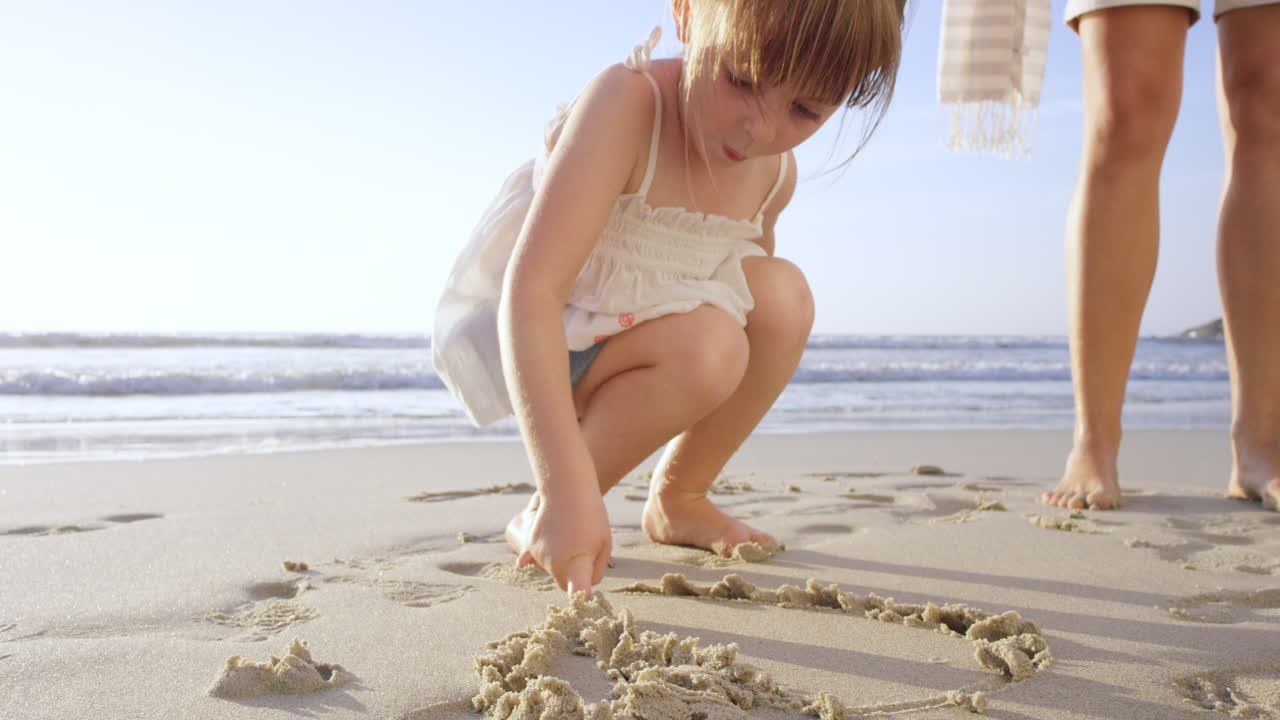 해가 지면 모래에 그림을 그리는 해변에서 즐겁게 놀고 있는 행복한 가족