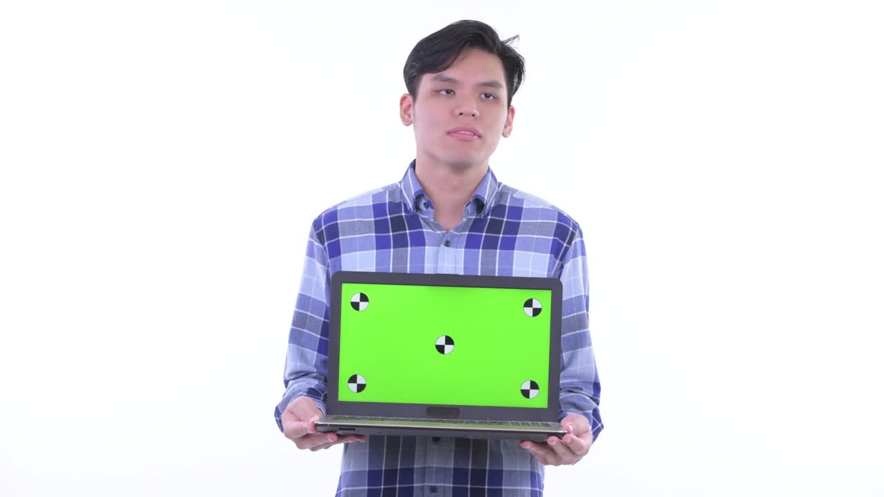 젊은 잘생긴 아시아 남자의 초상화로 녹색 화면으로 노트북을 보여주는 백색 배경에 고립된 복사 공간