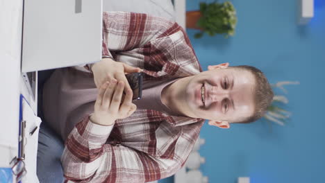 Vertical-video-of-Home-office-worker-man-getting-good-news-on-the-phone.