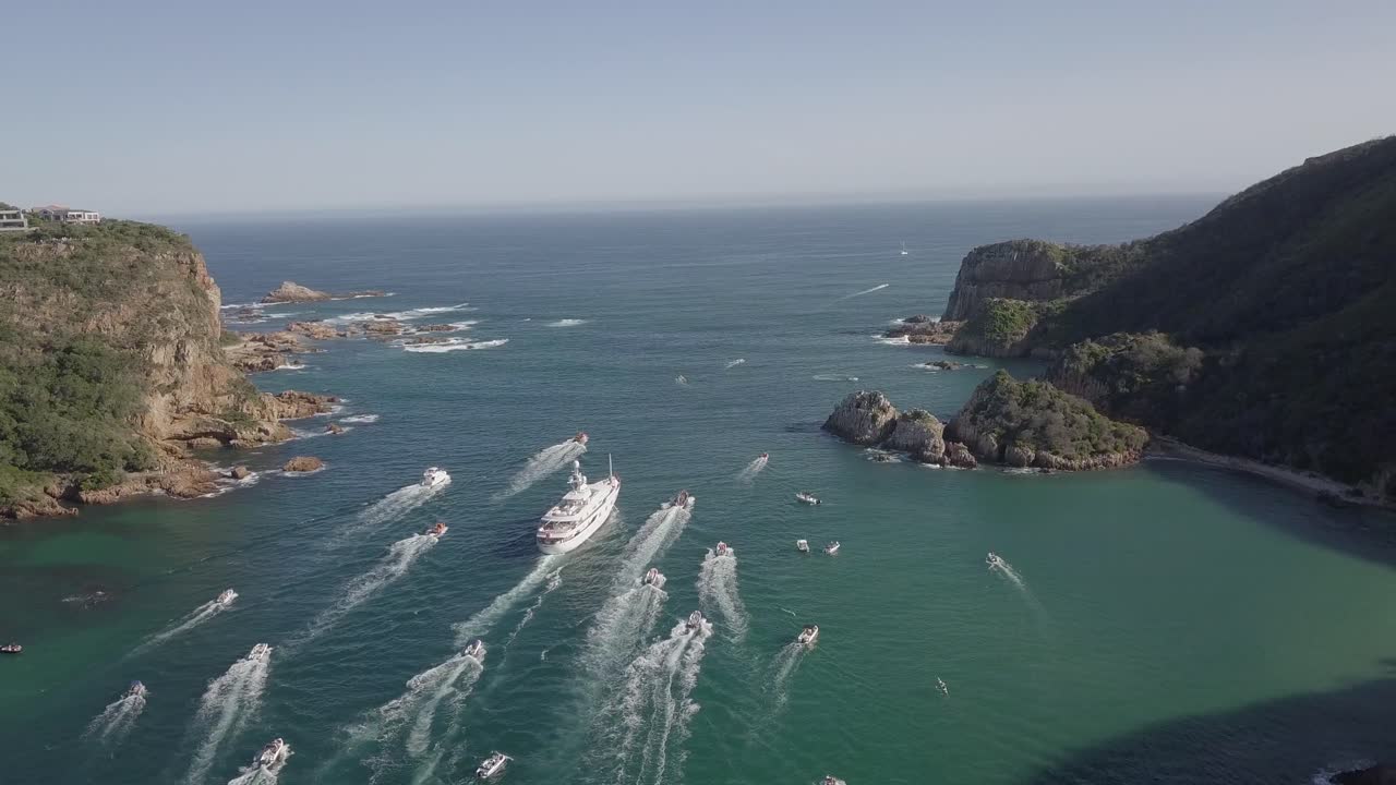 Yacht MV Katharine e persone che salutano passano le strette Knysna Heads verso il mare.