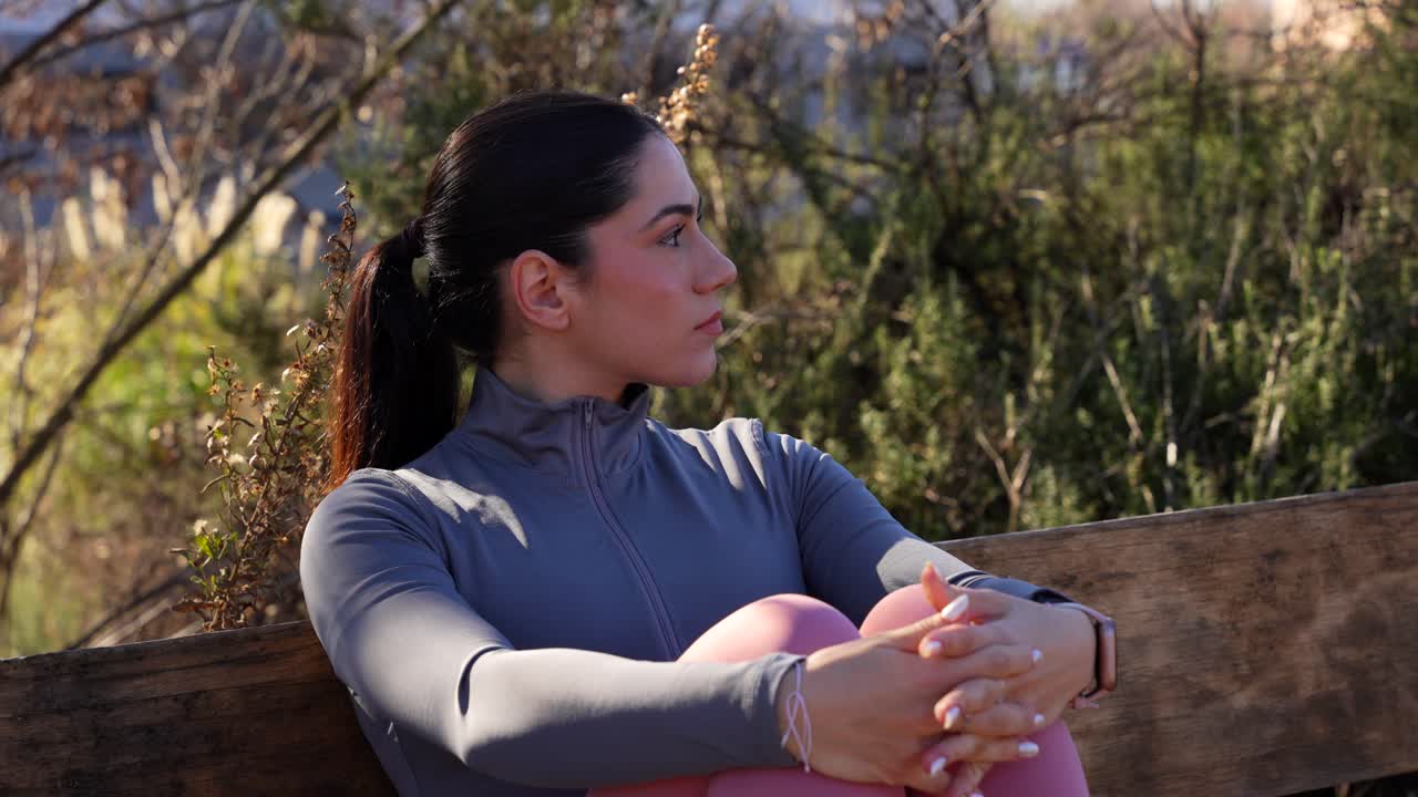 Woman resting on bench after workout plays with the thermal shirt zip. Close-up