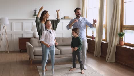 una pareja de jóvenes muy felices bailando con niños pequeños felices.