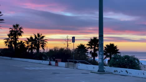 buildings palm trees silhouette tropical city, and sunrise and clouds time lapse in background