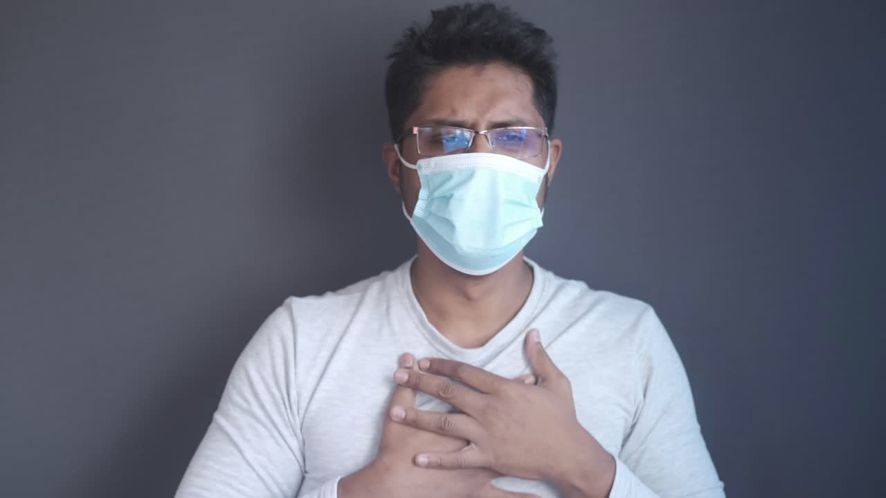 hombre con máscara experimentando dolor en el pecho