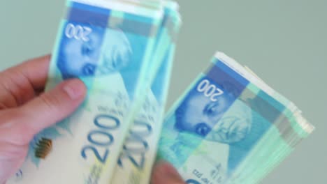 manos contando nuevos billetes de shekels, billetes en efectivo, por encima, de cerca.