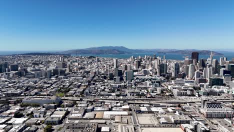 a wide panoramic aerial view of downtown san francisco, showcasing the extensive cityscape with high-rise buildings, the bay area, and landmarks like the golden gate bridge in the distance.