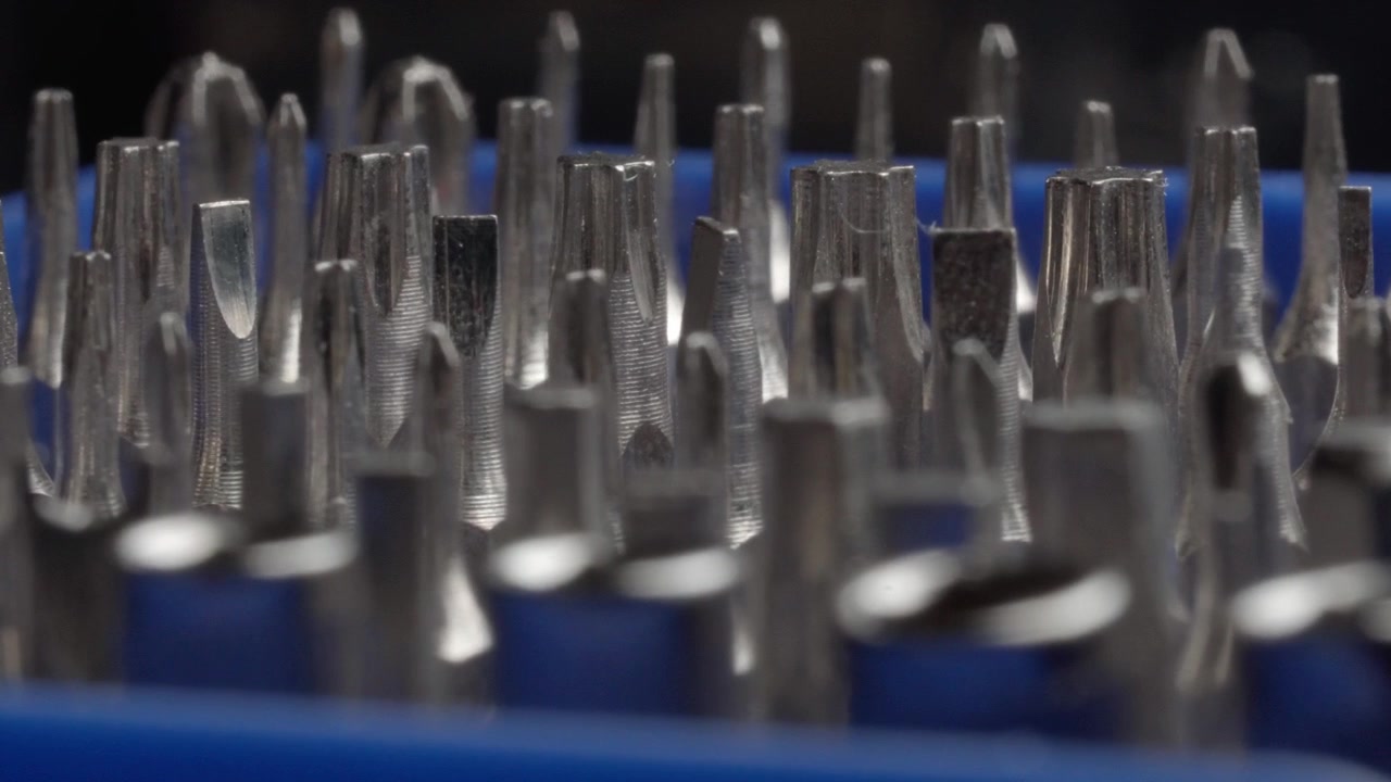 Macro primo piano di punte per cacciavite in metallo assortite disposte in un portautensili blu, che mostrano diverse forme e dimensioni delle punte per lavori di riparazione e manutenzione di utensili manuali