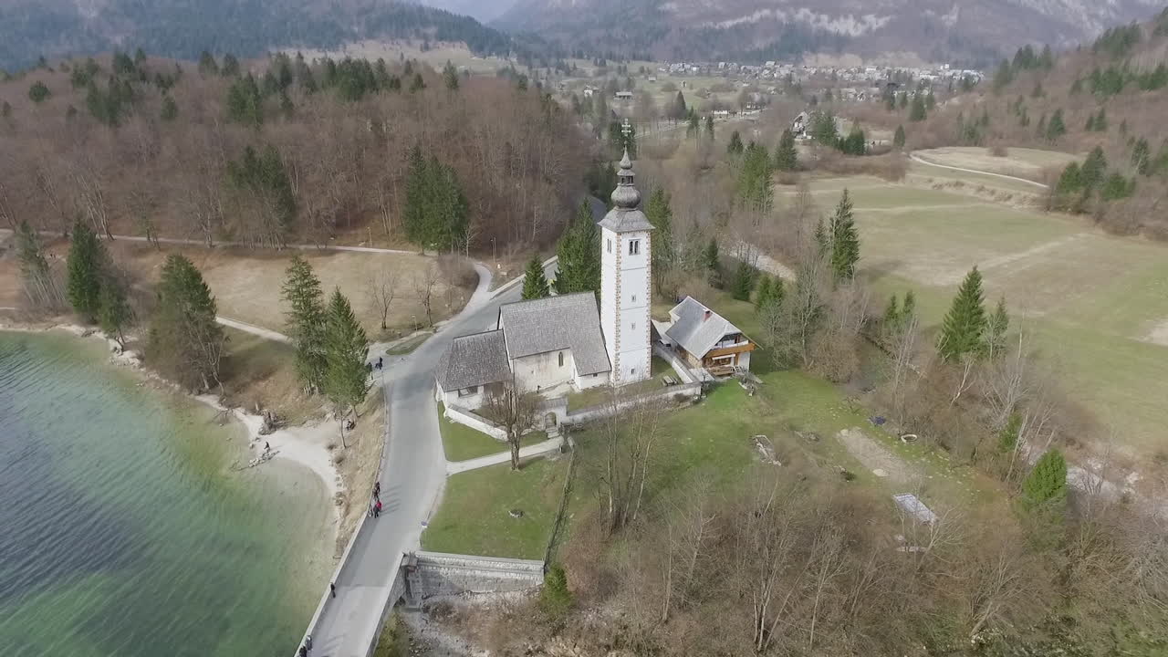 Vista da drone intorno a un ponte e una chiesa dal lago di Bohinj, Slovenia