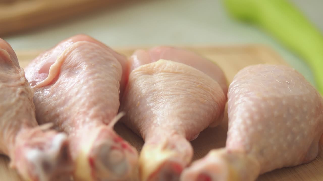 Raw chicken drumsticks and vegetables on a cutting board