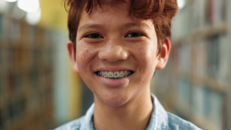boy with braces smiling in a library