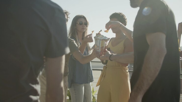 Happy friends drinking beer and eating nachos at rooftop party on a summer day