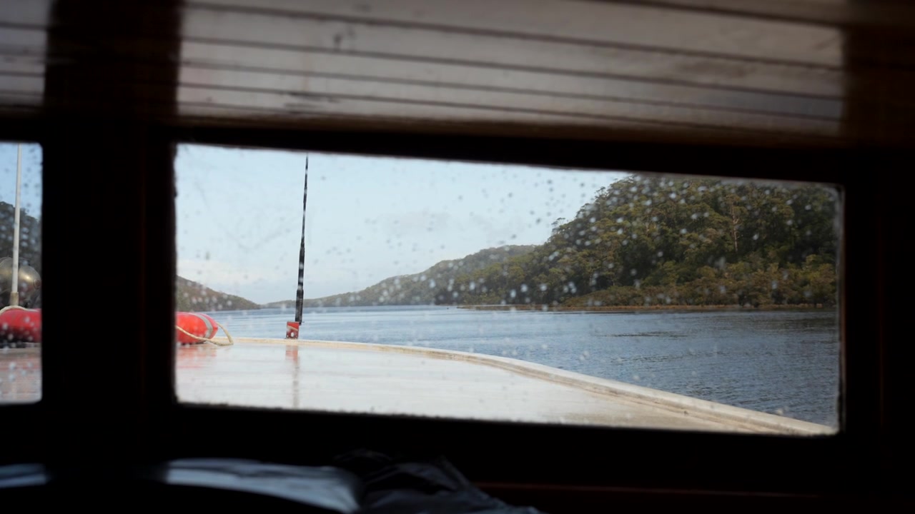 Vista pela janela frontal de um antigo barco a vapor, navegando rio abaixo. Imagens em câmera lenta. Cruzeiro no Rio Pieman. Corinna, Tasmânia, Austrália.