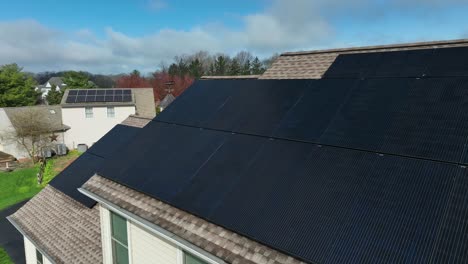 aerial view of black solar panels on roof of single family home and garage in modern housing area