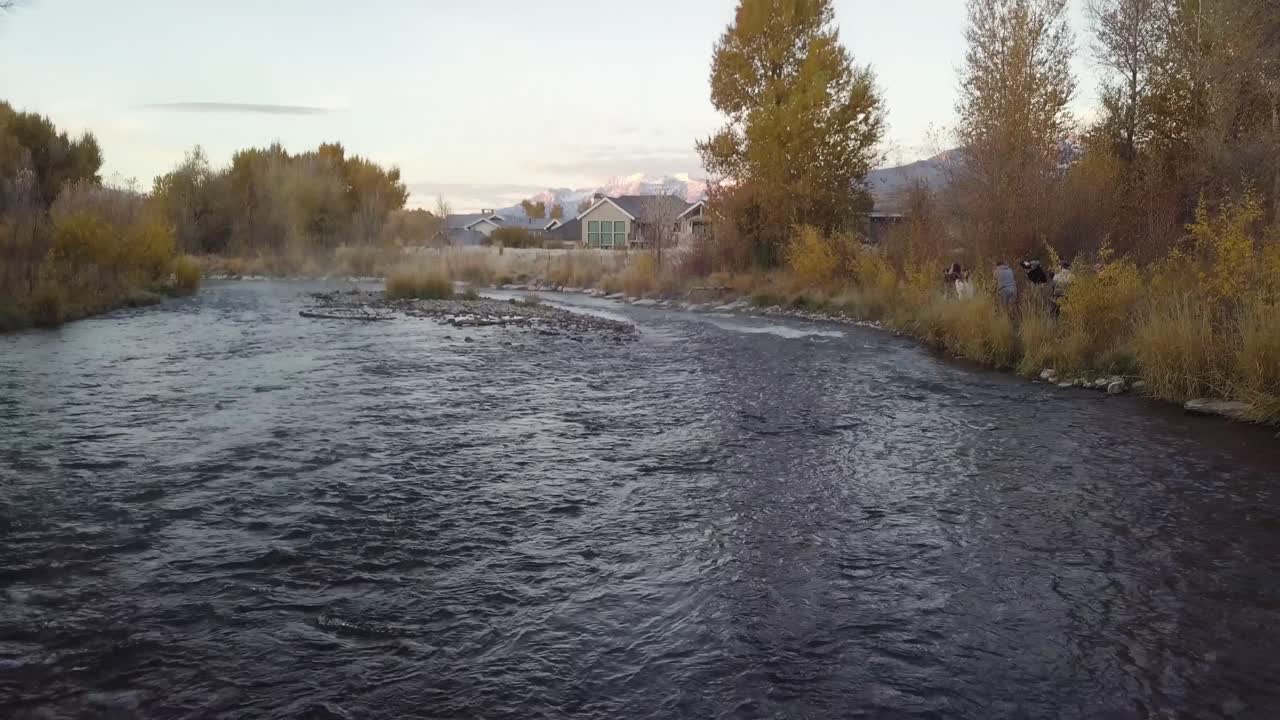 Strømmende klippefyldt bæk ved solopgang med gyldne efterårsfarver i et boligområde i Heber Utah - AERIAL DOLLY REVERSE TILT.