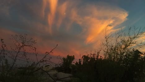 wide, windy time lapse of fast moving clouds and ever changing sky, as light recedes in the evening, revealing a shining moon