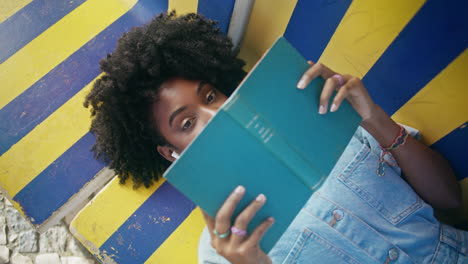 curly girl posing book lying on campus bench close up. student reading textbook