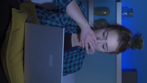 video vertical de una mujer mirando cansada y agotada en la computadora portátil por la noche.