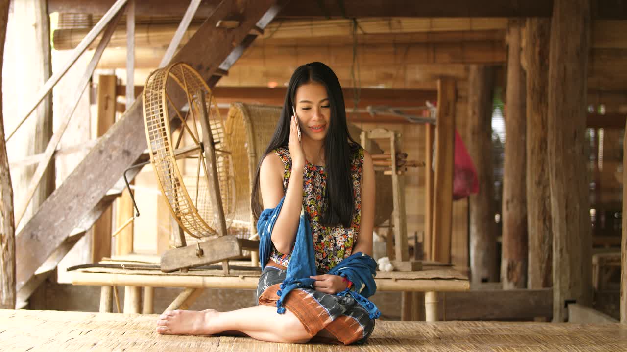 Woman talking on phone in a rural Thai village