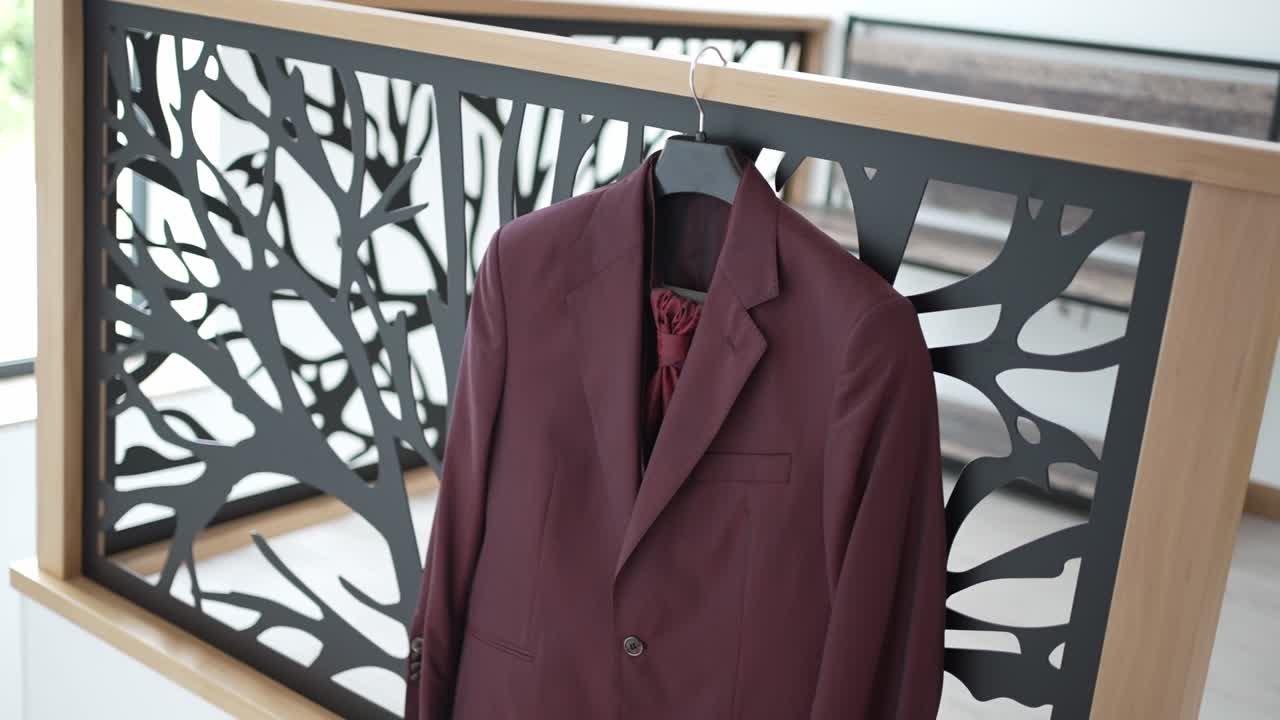 Burgundy suit jacket on a hanger, draped over a modern black and wood railing