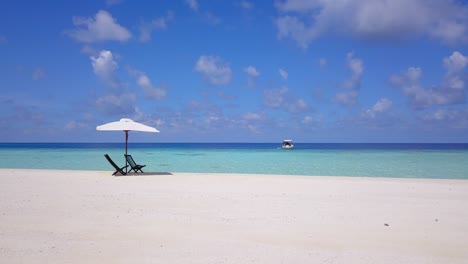 Un-Movimiento-Deslizante-Lento-En-Las-Playas-Blancas-Del-Mar-Caribe-Turquesa,-Con-Dos-Asientos-De-Madera-Vacíos-Bajo-Una-Sombrilla-Blanca