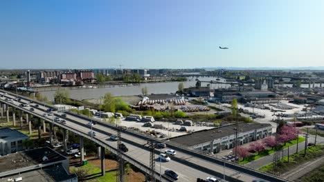 Traffic-On-The-Oak-Street-Bridge-Spanning-The-Fraser-River-With-An-Airplane-In-The-Sky-In-Metro-Vancouver,-Canada