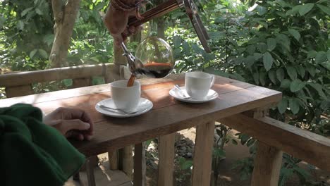 person pouring popular luwak coffee in cups in bali jungle bungalow