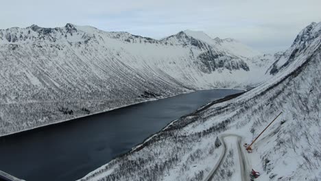 Drone-view-in-Tromso-area-in-winter-flying-over-a-fjord-surrounded-by-white-mountains-top-view-in-Norway