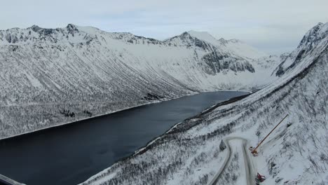 vista de avión no tripulado en el área de tromsø en invierno volando sobre un fiordo rodeado de montañas blancas vista superior en noruega