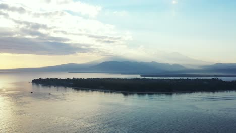 Bunter,-Heller-Himmel-Mit-Grauen-Und-Weißen-Wolken,-Die-über-Der-Silhouette-Einer-Tropischen-Insel-Hängen,-Umgeben-Von-Ruhigem-Meer-Bei-Sonnenuntergang,-Indonesien